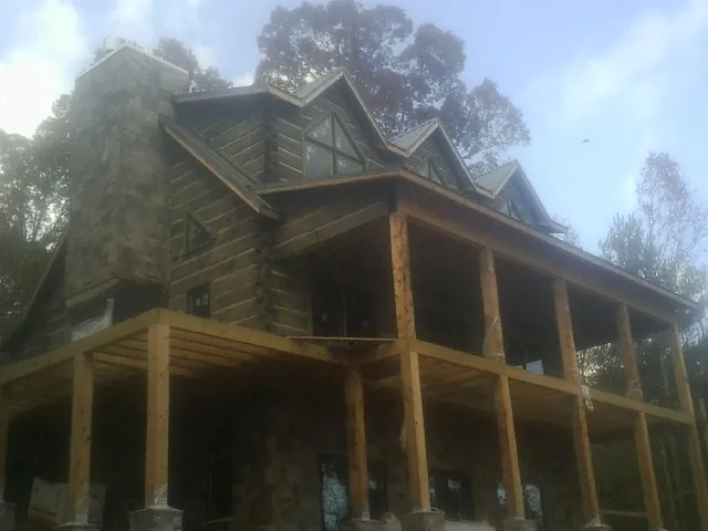 Stone chimney and dormers on a large log home with a timber porch in Richfield